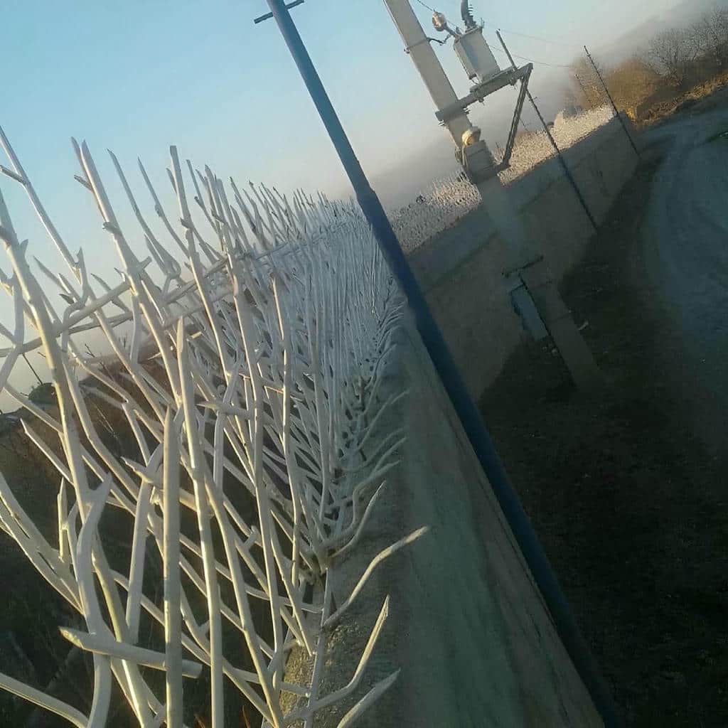 نرده سرنیزه ای مشکی روی دیوار سنگی