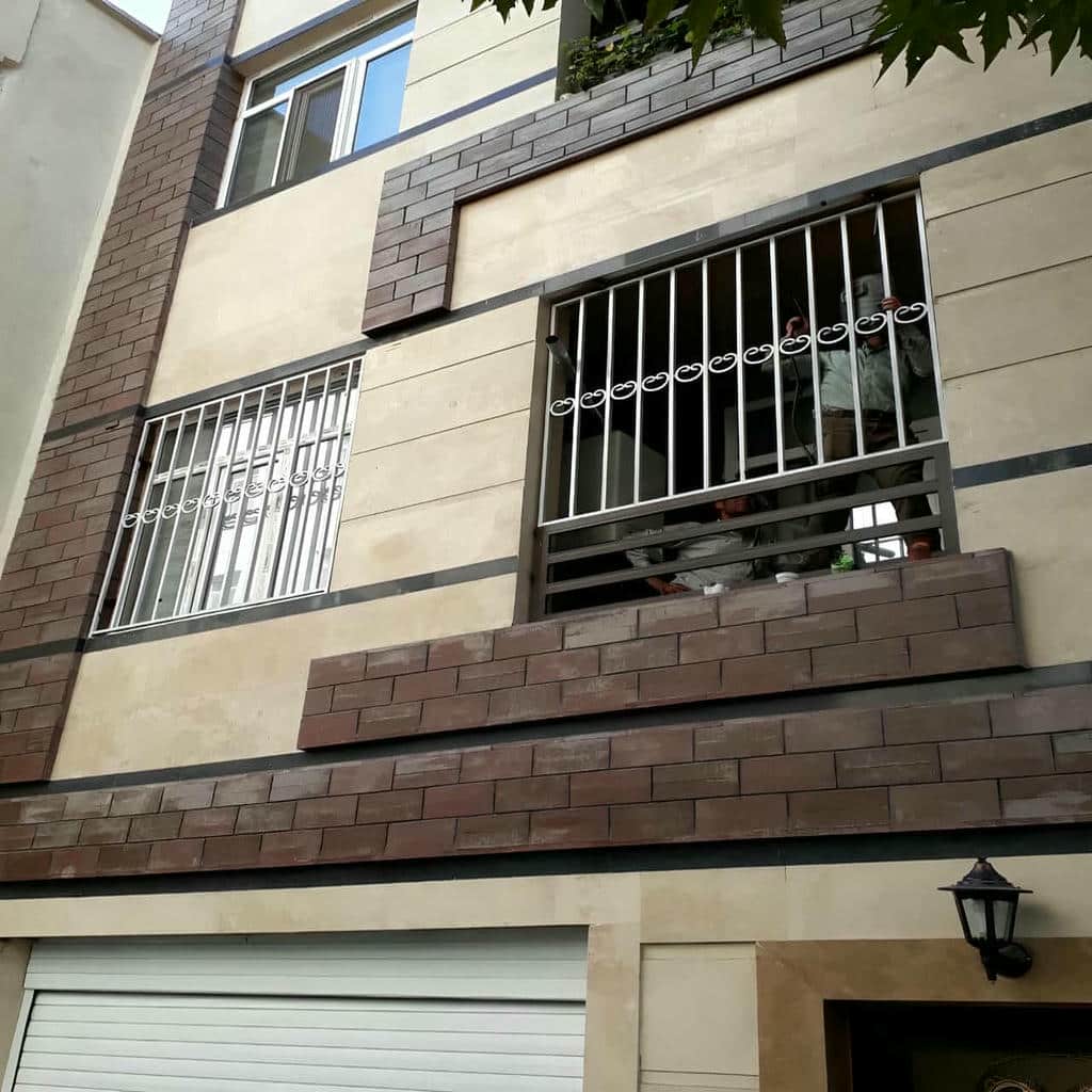 نرده پنجره سفید کنار دیوار سنگی ویلا در سنندج