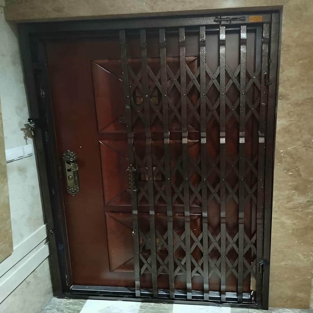گارد کشویی نقره‌ای مقابل درب چوبی ساختمان